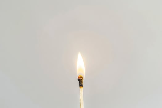 Single burning matchstick against white background. Concept of ignition, heat, energy, simplicity, and minimalism. Copy space photo