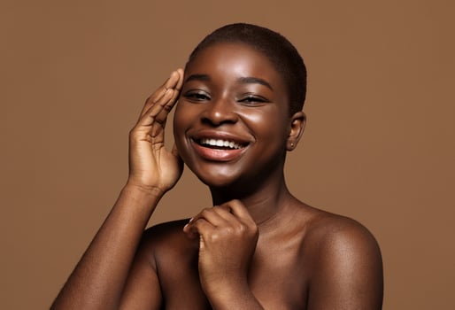 Essential Beauty. Portrait Of Nude Attractive African American Woman Touching Her Smooth Skin, Pretty Black Female With Short Hair Smiling And Looking At Camera, Over Brown Background, Copy Space photo