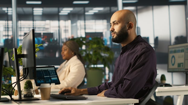 Arab man reviewing financial graphs, analyzing key performance indicators. Middle Eastern employee in workspace looking over data trends and strategic insights, camera A photo
