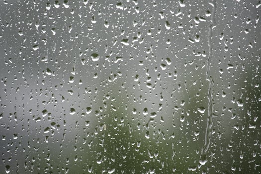 Raindrops on a window create a beautiful, abstract scene with a blurred background. photo