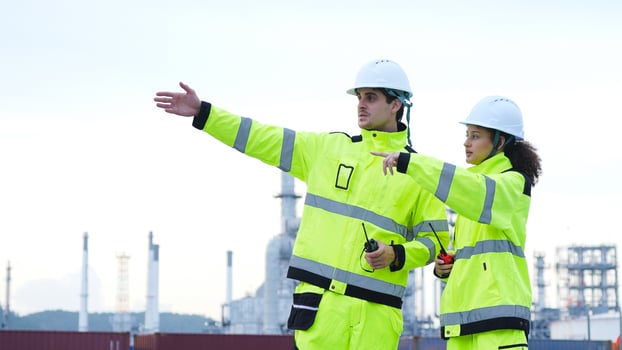 Industrial Engineers Discussing Plans at a Refinery Site, Two Safety-Clad Workers Pointing and Collaborating at an Industrial Facility, Teamwork and Supervision at an Outdoor Chemical Plant photo