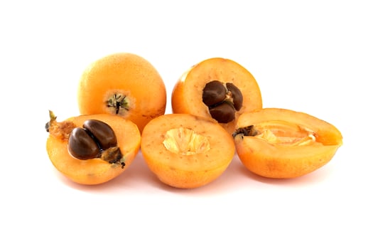 Fresh loquats, whole and halved, showing seeds, on white background photo