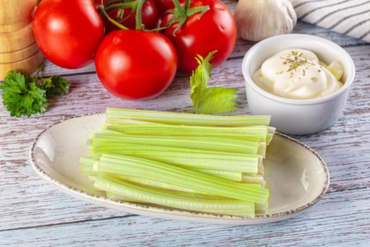Celery sticks and tomatoes on a white plate photo