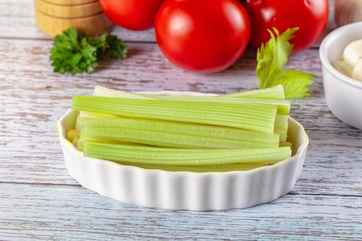 A bowl of celery and other vegetables on a wooden table photo