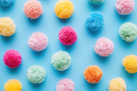 Colorful yarn pom-poms arranged on a light blue background photo
