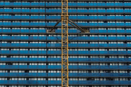 A tower crane attached to the wall of a blue building, construction site photo