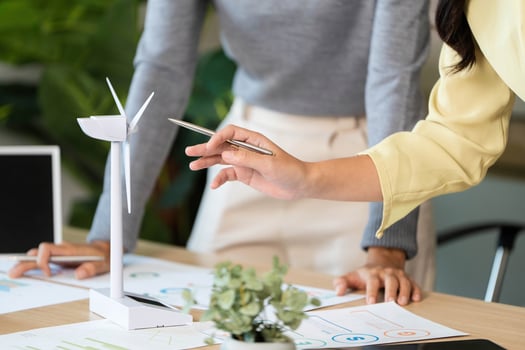 ESG Collaboration. Team discussing renewable energy strategies with wind turbine model. photo