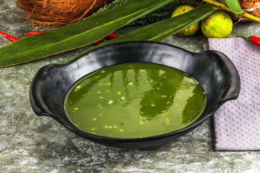A bowl of green sauce with coconut and other ingredients photo