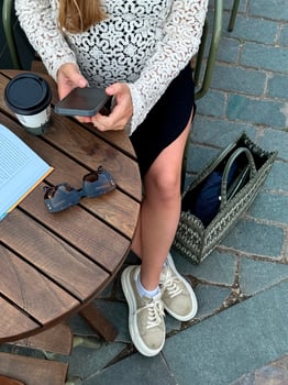 Woman using smartphone while enjoying coffee and reading outdoors in a stylish cafe setting photo