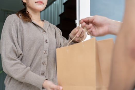 Happy smile woman receives paper bag parcel of food from courier front house. Delivery man send deliver express. online shopping, paper container, takeaway, postman, delivery service, packages photo