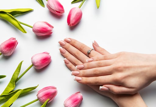 Woman showing french manicure near fresh pink tulips photo