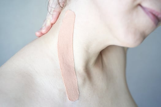 Close-up of elastic beige kinesiology tape on female caucasian shoulder for muscle support and pain relief. photo