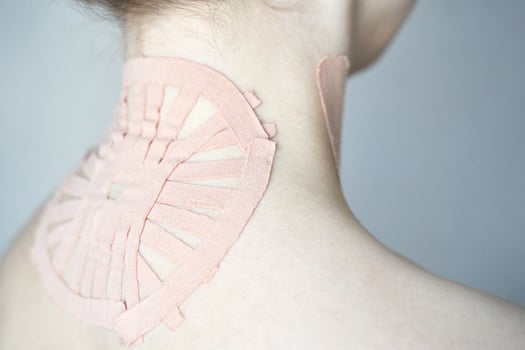 Female adult with therapeutic kinesiology tape applied to neck for pain relief and support. photo