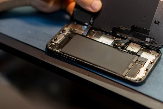 Phone Repair Technician Replacing Battery in Smartphone at a Workshop During the Day photo
