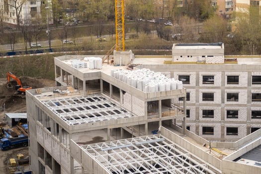 Construction Site Showcasing Progress on a Multi-Story Building With Cranes and Materials Present in an Urban Landscape During Daytime photo