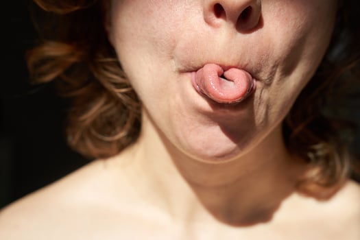 Young caucasian female demonstrating unique tongue rolling skill in close-up portrait. photo