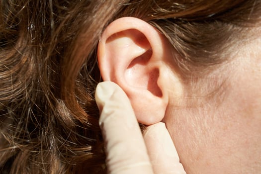 Female caucasian adult ear examined by gloved hand in close-up image highlighting ear health. photo