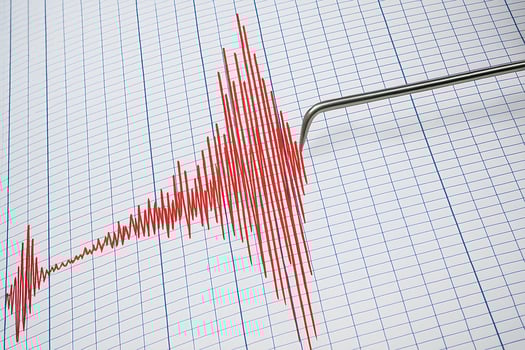 A seismograph records an earthquake by drawing red lines on paper to indicate strong tremors photo