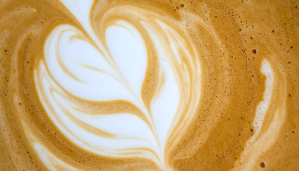 top view of latte art heart swirl in milk foam on espresso coffee surface, creamy frothy texture in warm cafe atmosphere photo