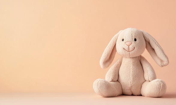 A stuffed rabbit is sitting on a beige background photo
