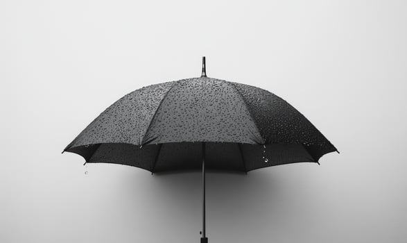 A black umbrella with raindrops, gray wall background photo