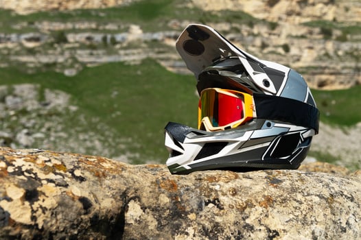 Professional full face helmet with goggles mask lies on a rock against the backdrop of a mountain landscape in the mountains on a sunny day. Used helmet for mountain biking and moto sports. photo