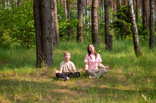 A woman and a boy meditating in the woods photo