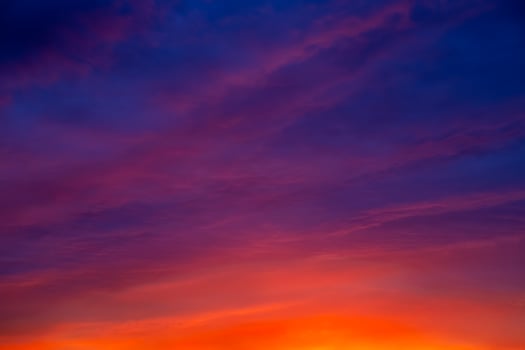 Evening sky with deep purple and orange hues against the setting sun. photo