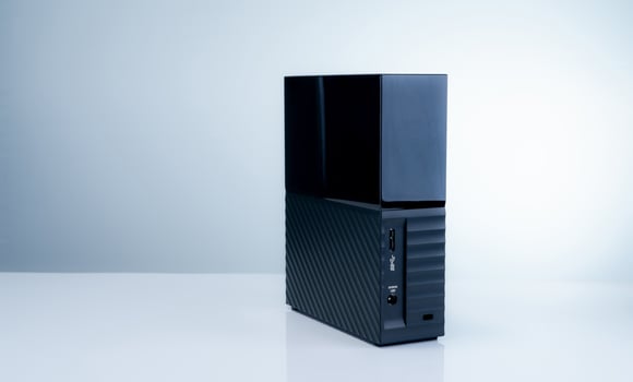 Black solid state external hard drive on white background, perfect for digital data storage and fast backup solutions in modern offices, tech workspaces, and remote setups. Portable SSD device. photo
