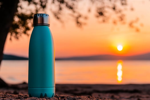 A blue water bottle sitting on the beach at sunset photo