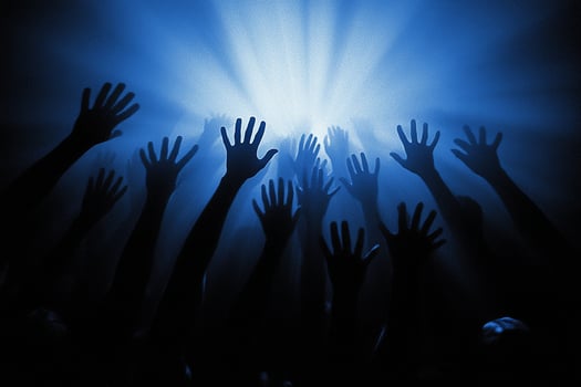 Hands reaching up in the air at a concert photo