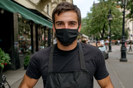 A man wearing a black face mask on a city street photo
