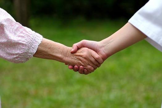 A nurse holding the hand of an elderly woman photo