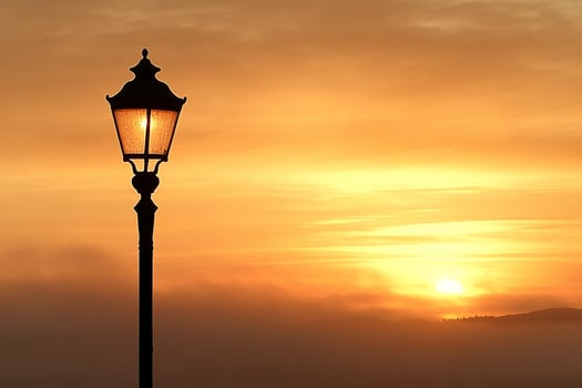 A street light is silhouetted against a sunset photo