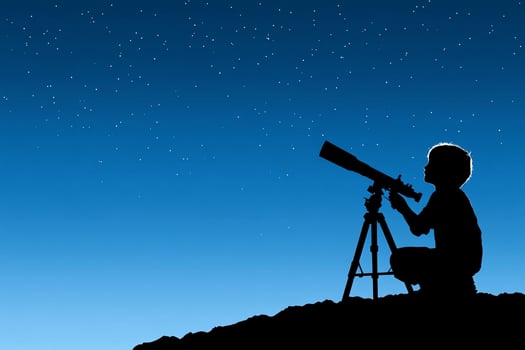 A silhouette of a boy looking through a telescope photo