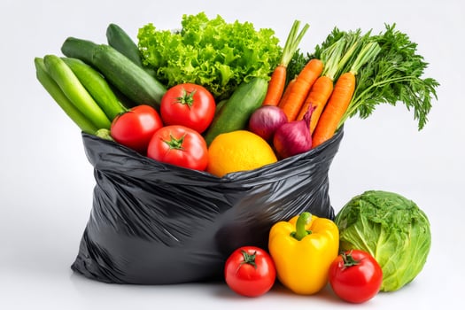 Fresh vegetables overflowing from black plastic shopping bag photo