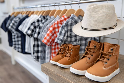 Children's fashion boutique displaying plaid shirts, a summer hat and leather boots photo