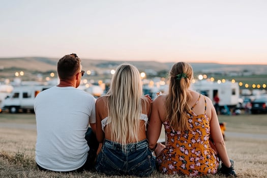 Three people sitting on the grass at a festival photo
