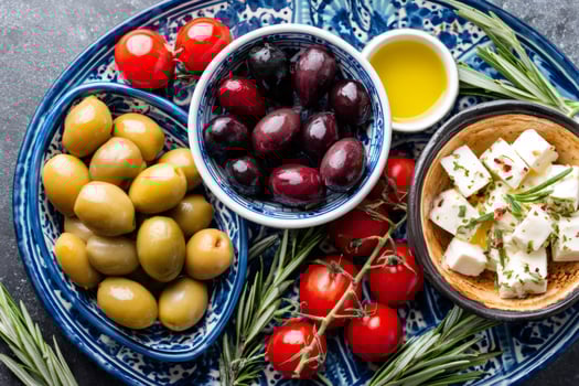 Mediterranean diet concept featuring green and black olives, cherry tomatoes, feta cheese, rosemary and olive oil photo