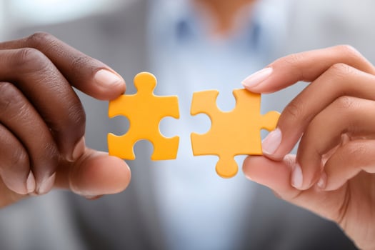 Businesspeople joining two puzzle pieces, teamwork and collaboration concept photo