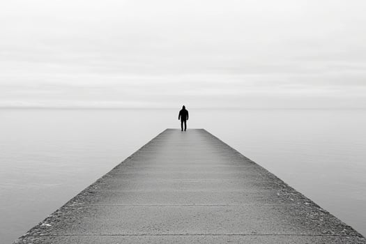 A person standing on a pier looking out to the ocean photo