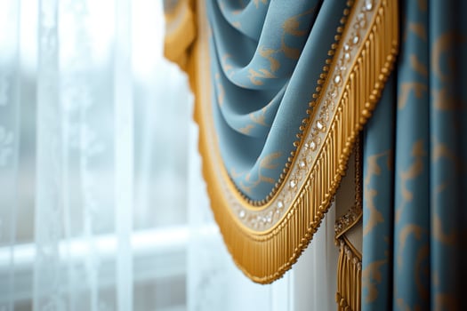 Elegant blue curtain with golden fringe hanging by the window photo