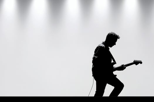 Silhouette of a man playing guitar in front of a spotlight photo