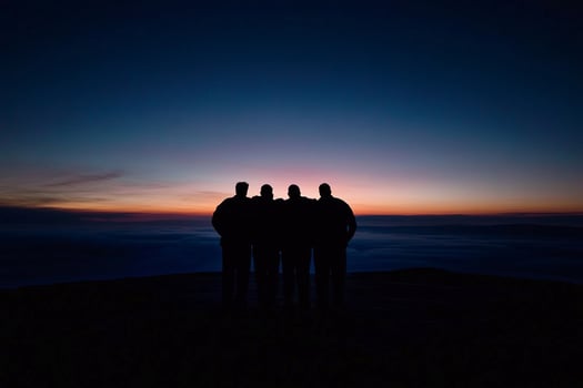 Three people standing on top of a mountain at sunset photo
