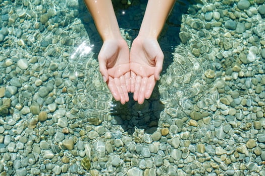 A person's hands are in the water with pebbles photo