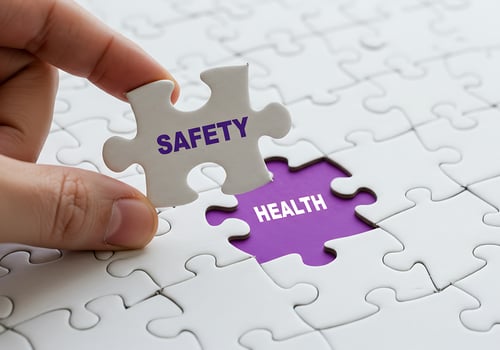 Hand placing 'Safety' puzzle piece to complete 'Health' in a jig photo
