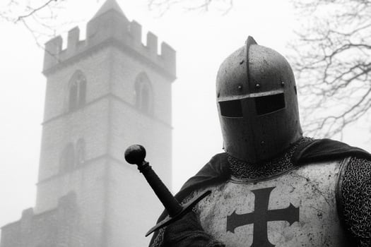 A knight in armor stands in front of a church photo