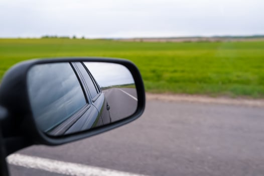 A car side view mirror is seen on the road photo