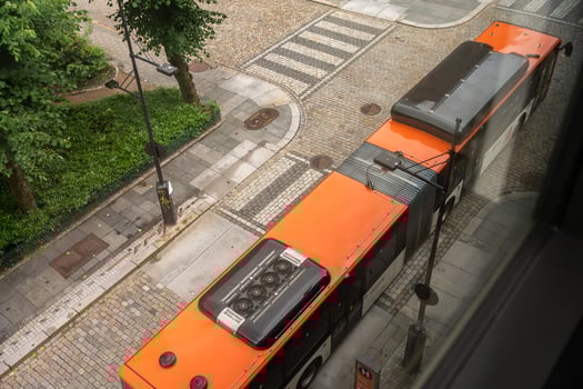 Bergen, Norway - July 7, 2024. Articulated city bus passing on cobblestone street seen from above photo