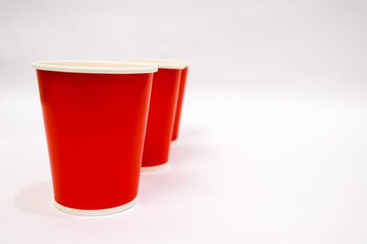 Three red disposable cups lined up against a plain white background with copy space photo